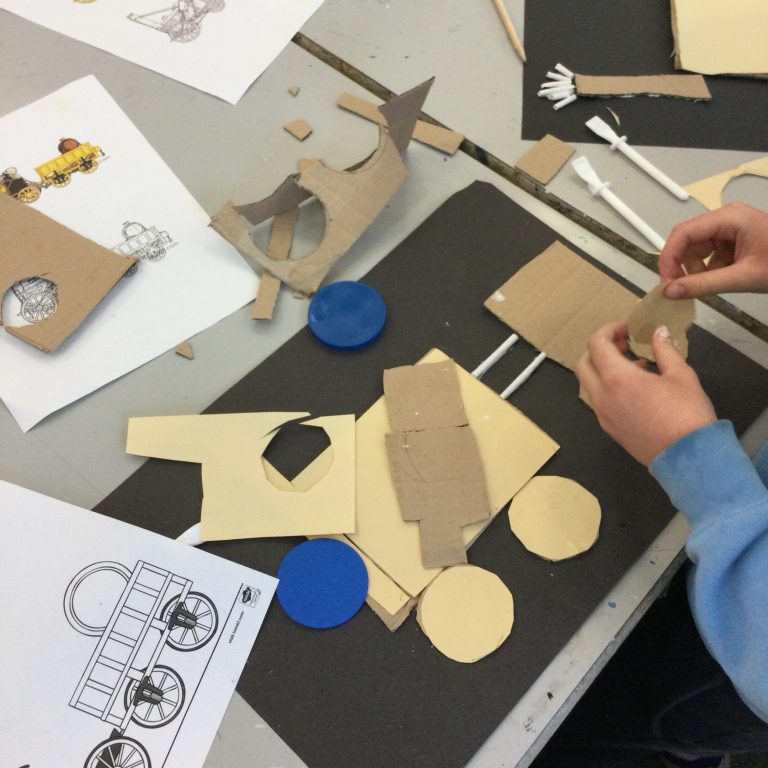 student adding cardboard to paper