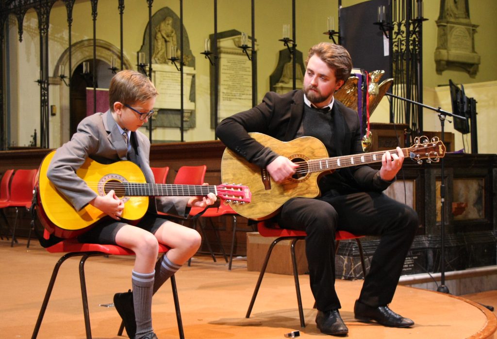 child and his teacher playing the guitar