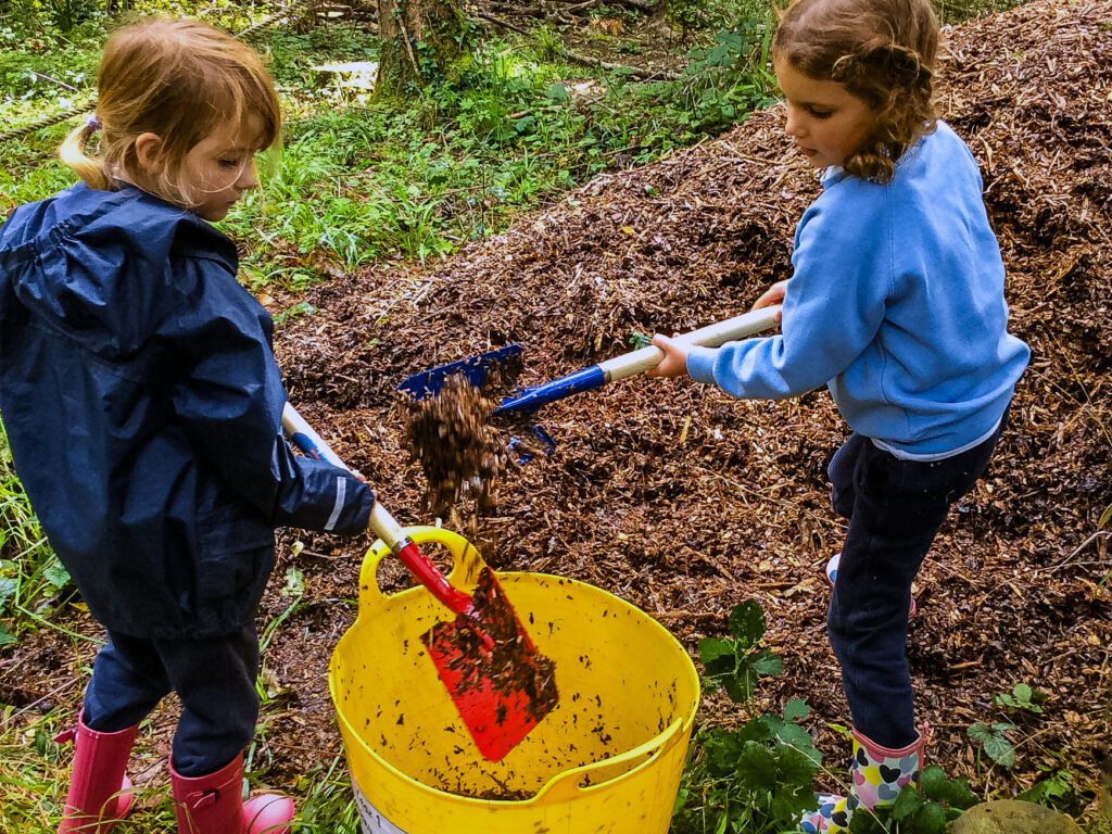 student shovelling leaves into a bucket