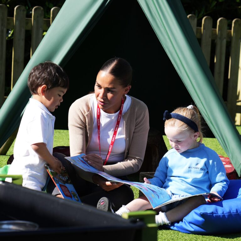 Teacher reading a book with 2 children listening in